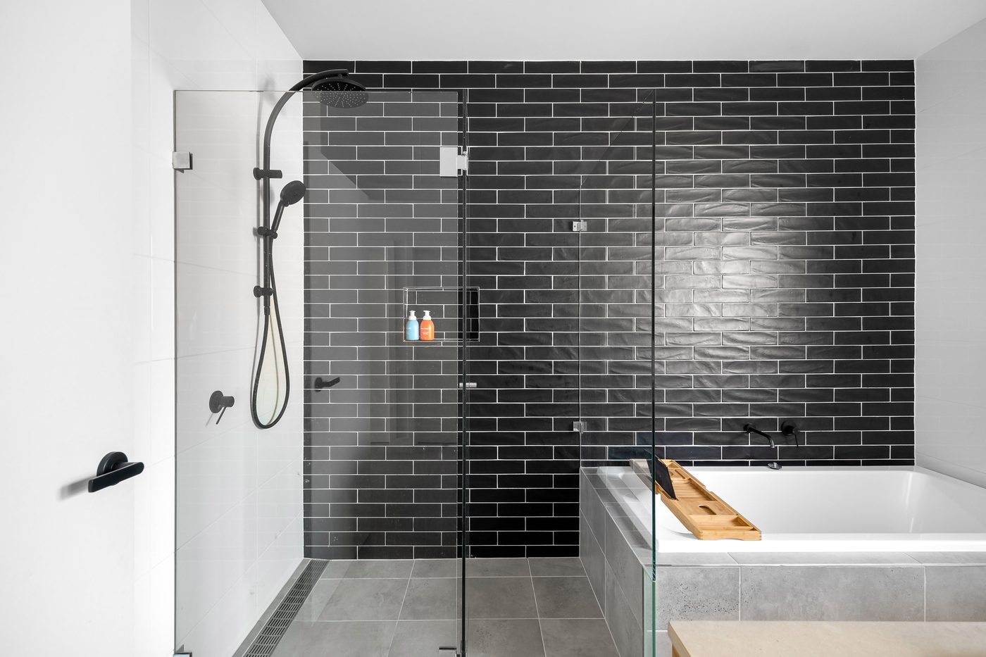 Bright modern bathroom with a glass walk-in shower, black tiles and black fittings