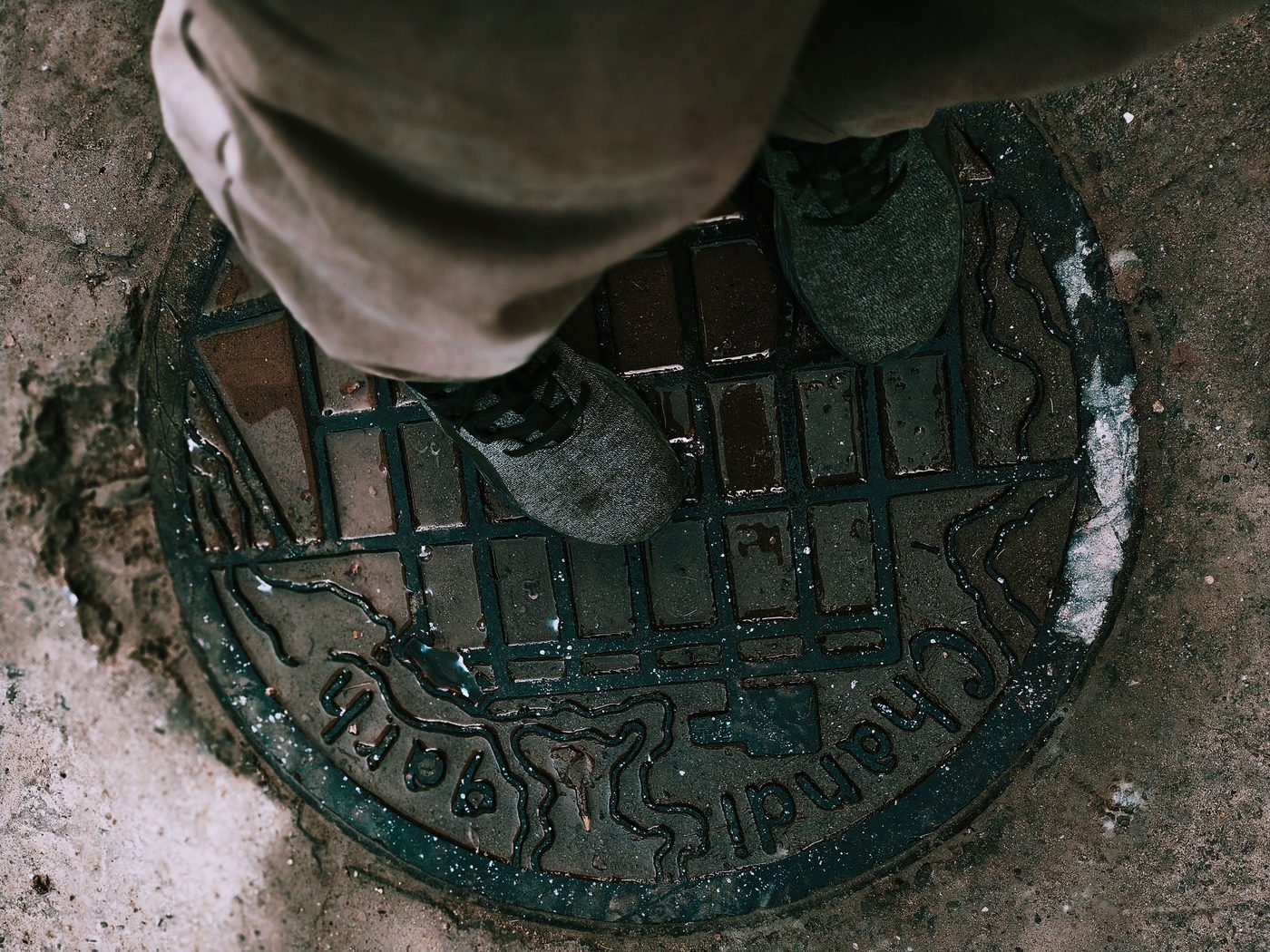 Boots standing on an old cast iron drain cover