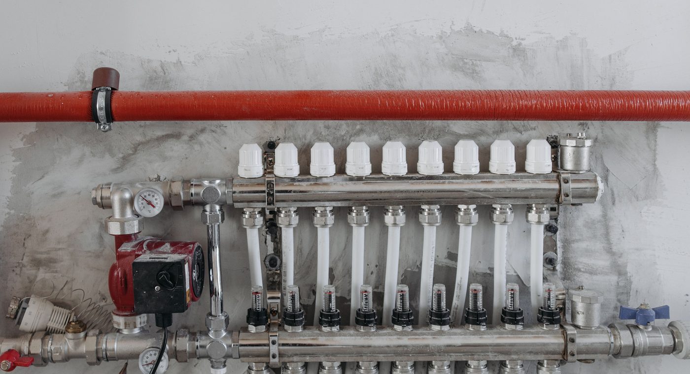 Heating manifold with a pump, gauges and flow meters on a plastered wall